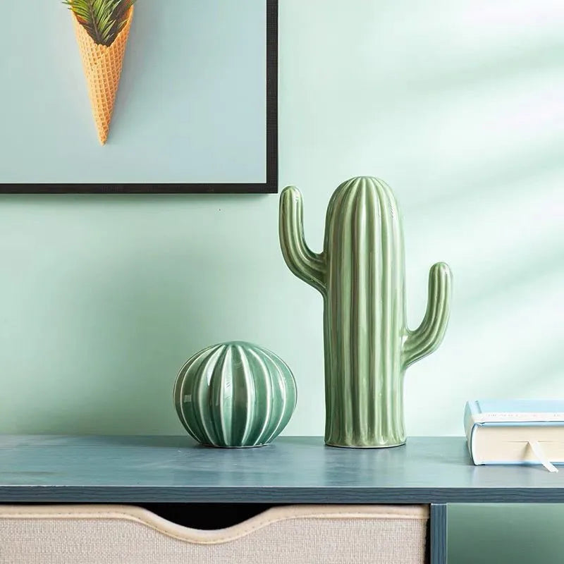 Two green cactus-shaped vases on a surface with a light green wall in the background.
