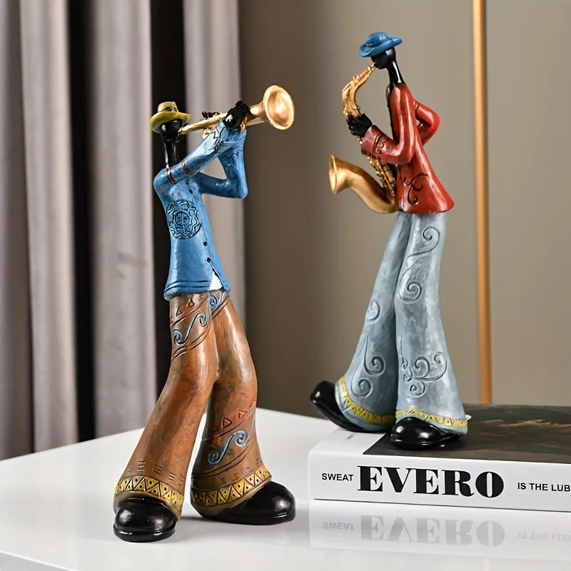 Two decorative figurines of musicians playing a trumpet and saxophone on a white surface with a blurred background.