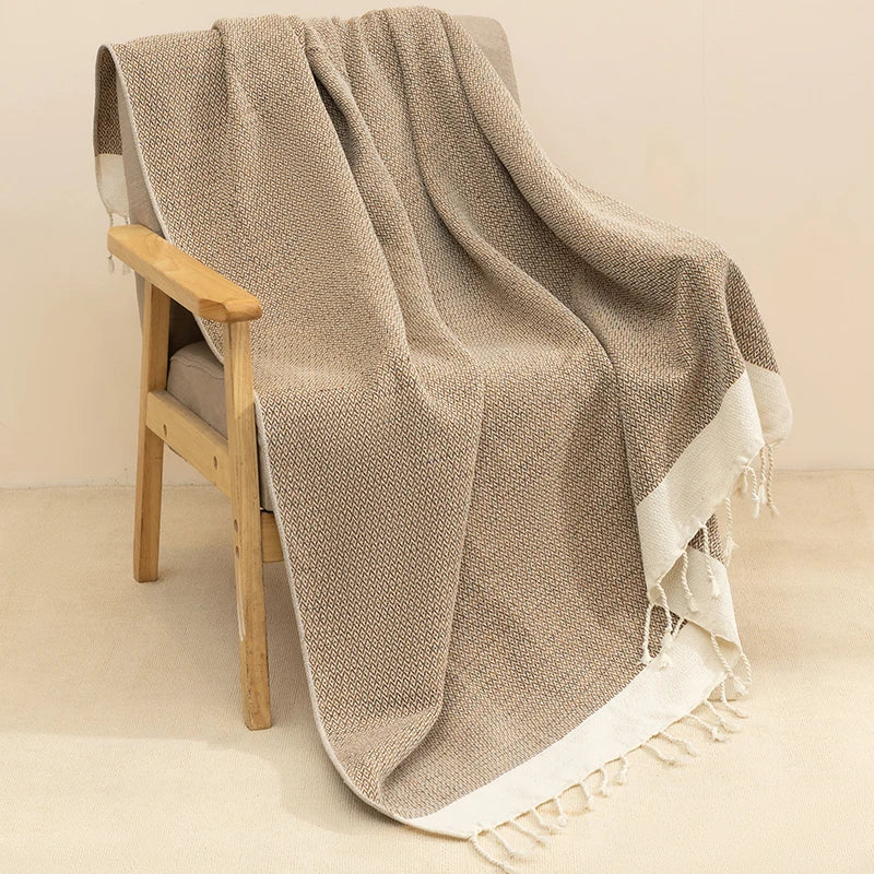 Beige textured throw blanket draped over a wooden chair on a beige background