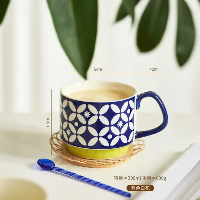 Blue and white floral-patterned mug on a coaster with a spoon, on a light surface.