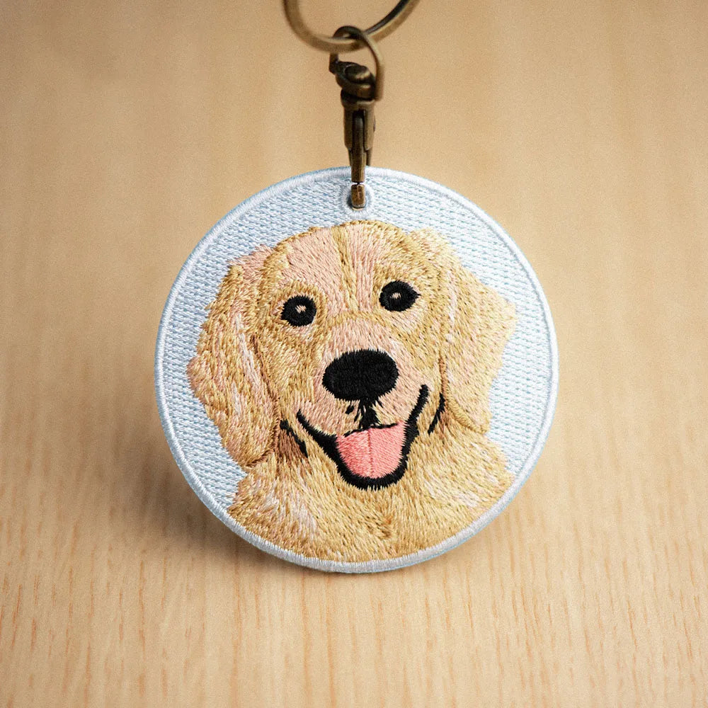 Embroidered keychain with a dog's face on a wooden surface