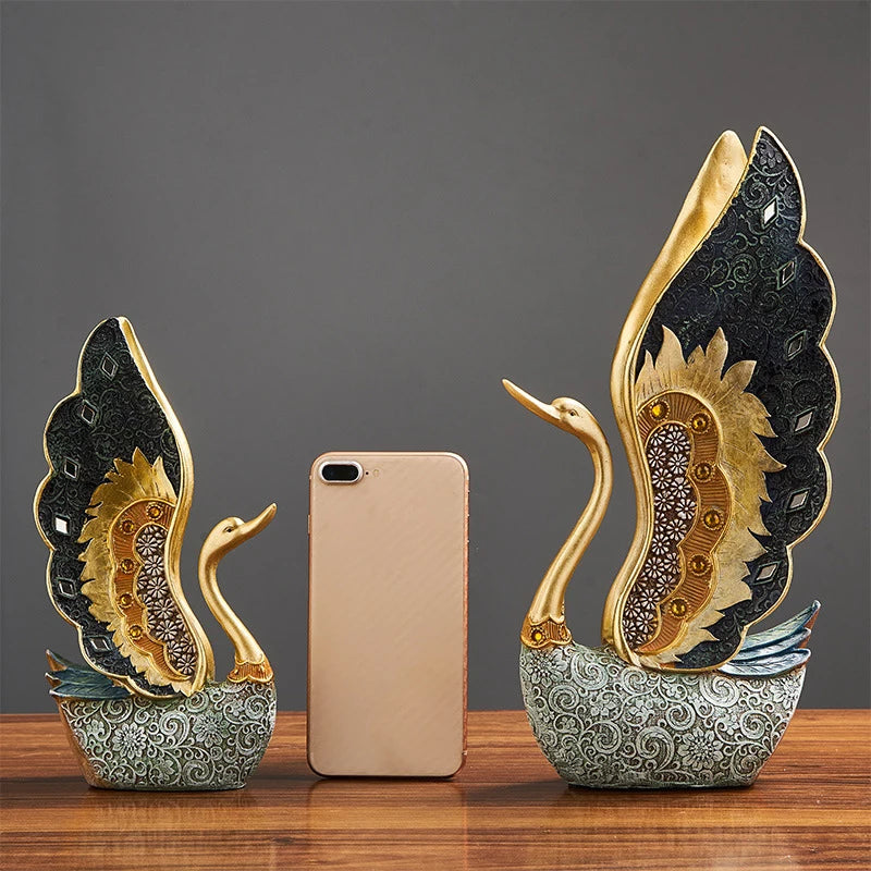 Decorative swan sculptures with a phone for scale on a wooden surface.