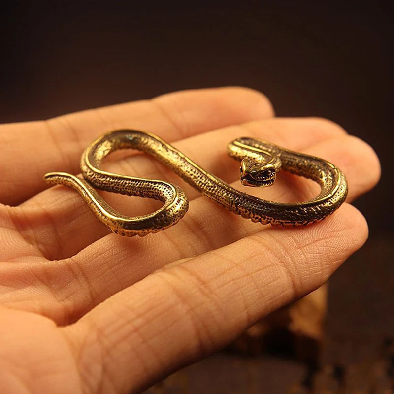 Gold snake-shaped object held in a hand with a warm brown background