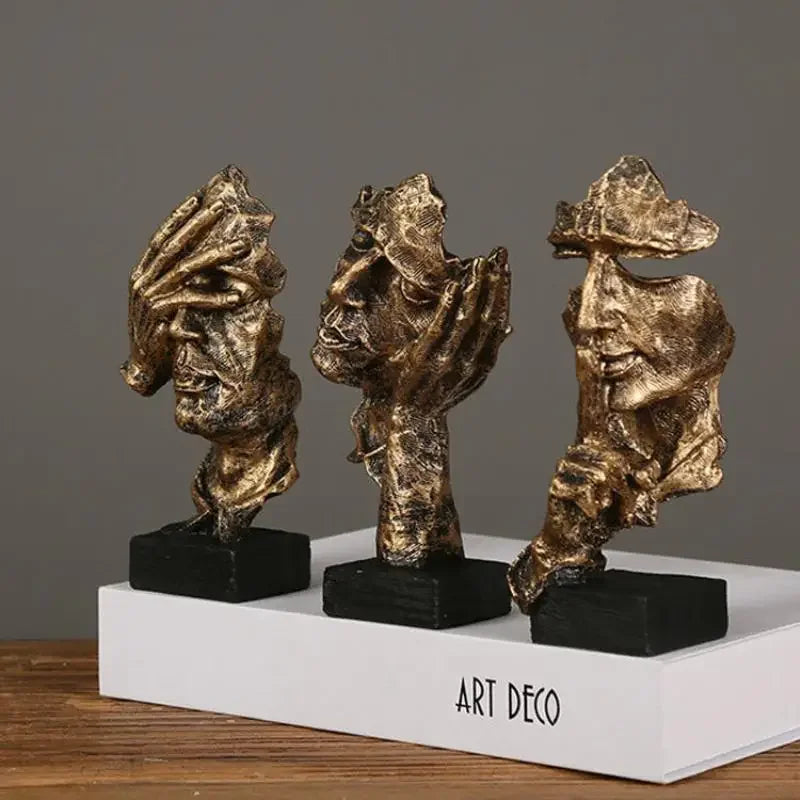 Three artistic sculptures on a wooden surface in bronze on a wooden surface and grey background