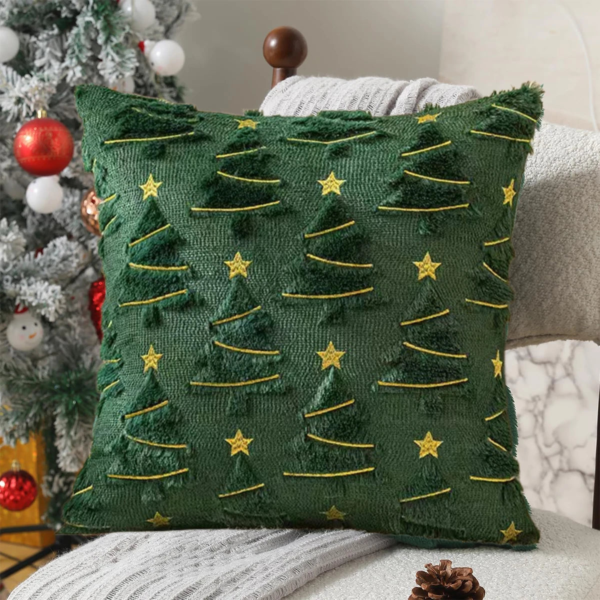 Green pillow with Christmas tree pattern on a couch next to a decorated Christmas tree.