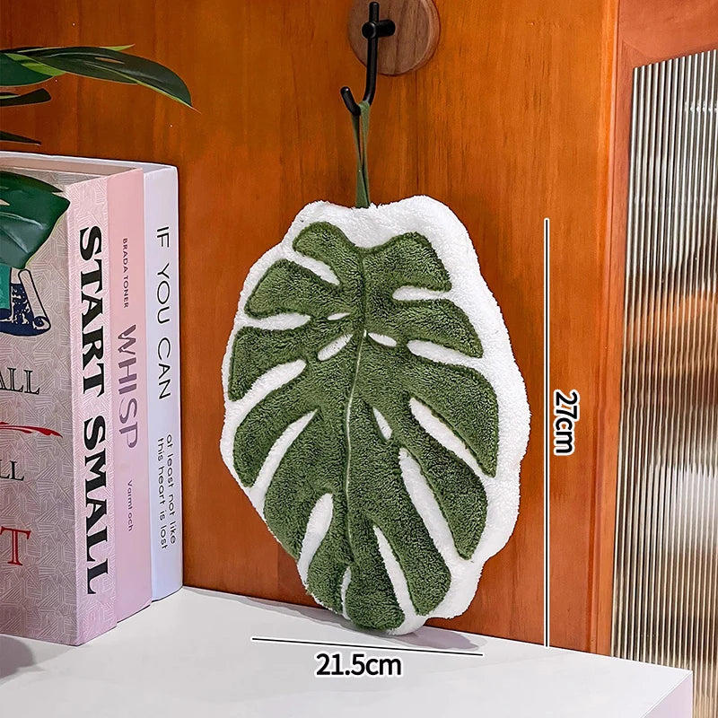 Green leaf-shaped towel hanging on a hook with books and a ruler for scale.