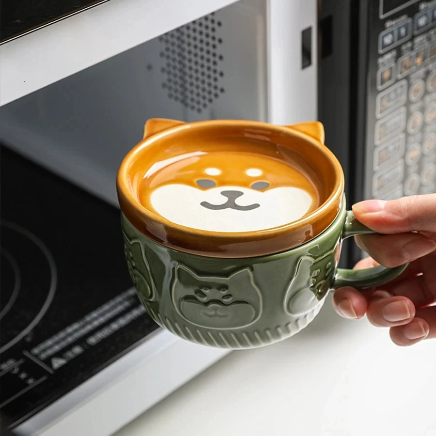Person holding a cat-shaped mug with a paw print design over a cup of coffee.