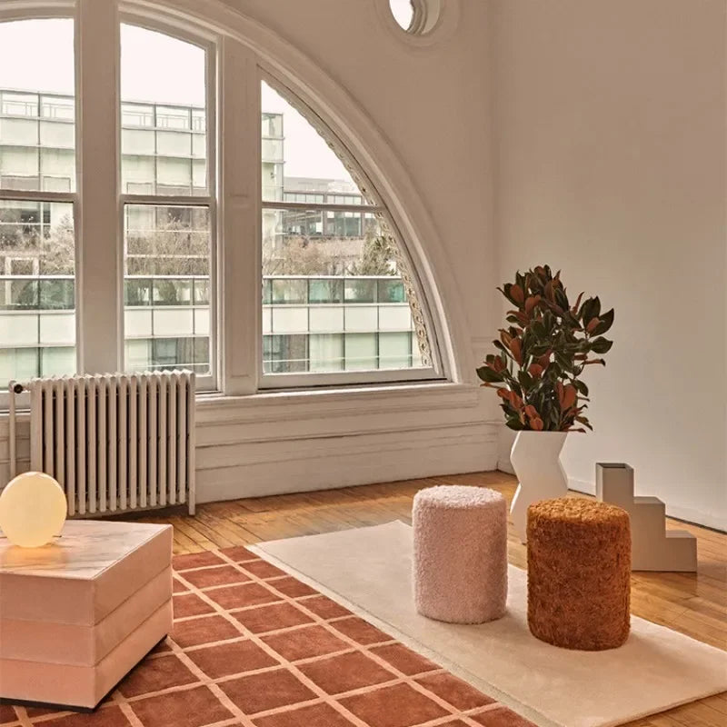 Modern interior with a large arched window, decorative plants, and colorful stools.