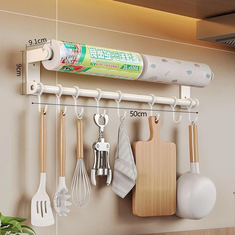 Wall-mounted kitchen organizer with hooks holding utensils and a roll of paper towels.