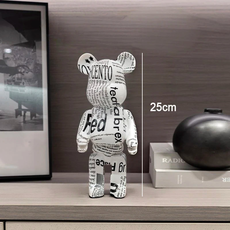 A bear-shaped collectible figure made from printed newspaper text stands on a shelf in an interior setting. A vertical measurement marker reads 25cm beside the figure.