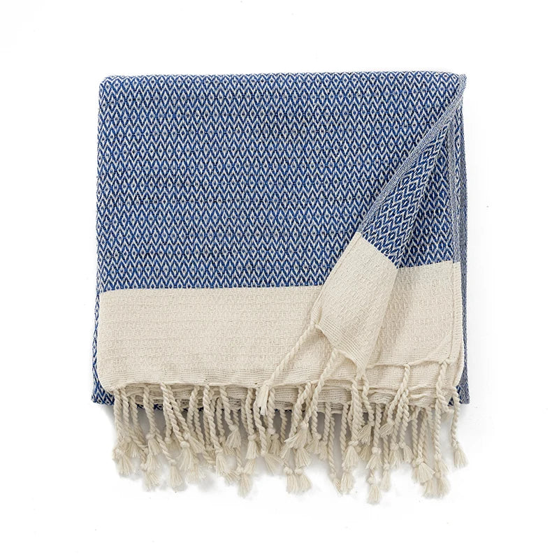 Blue and white patterned throw with fringes on a white background