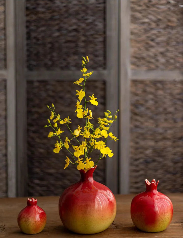 Decorative red and yellow vase with pomegranate-shaped objects on a wooden surface, brand 'PINGZHI' visible.
