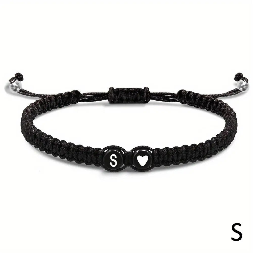 Black braided bracelet with letter 'S' charm on a white background