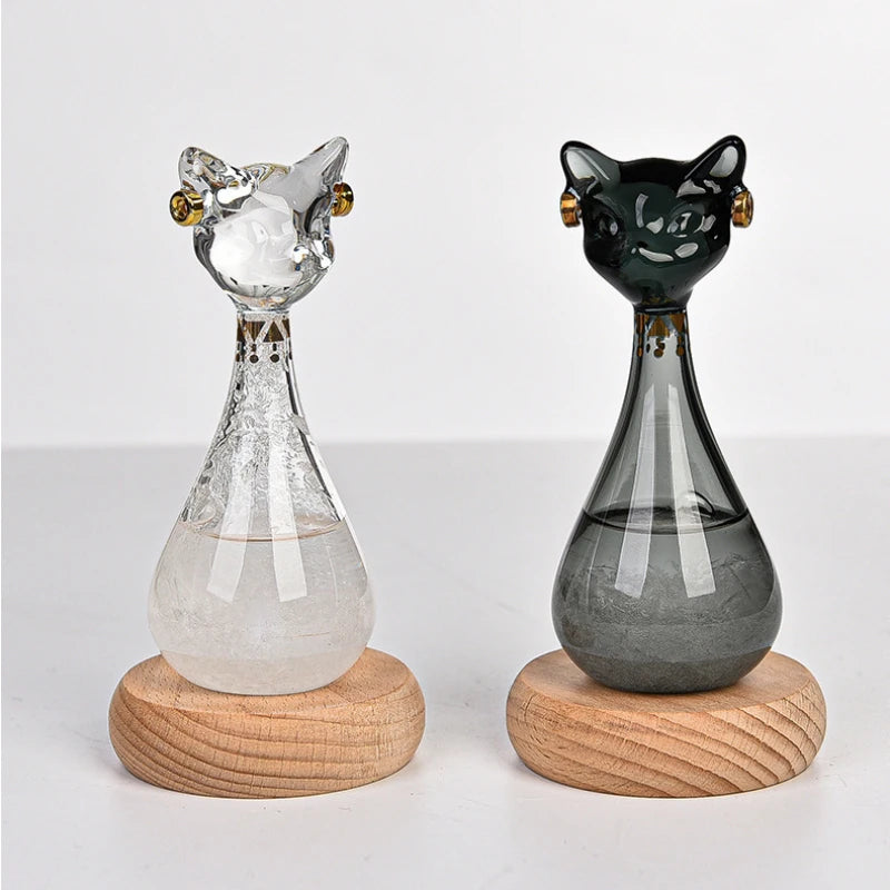 Two glass cat-shaped objects on wooden bases against a white background