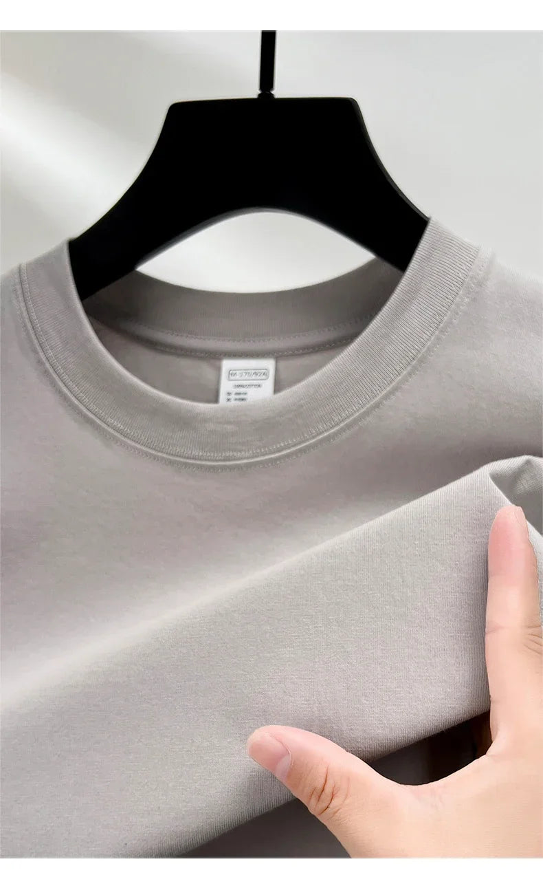 Gray t-shirt on a hanger with a hand touching the fabric