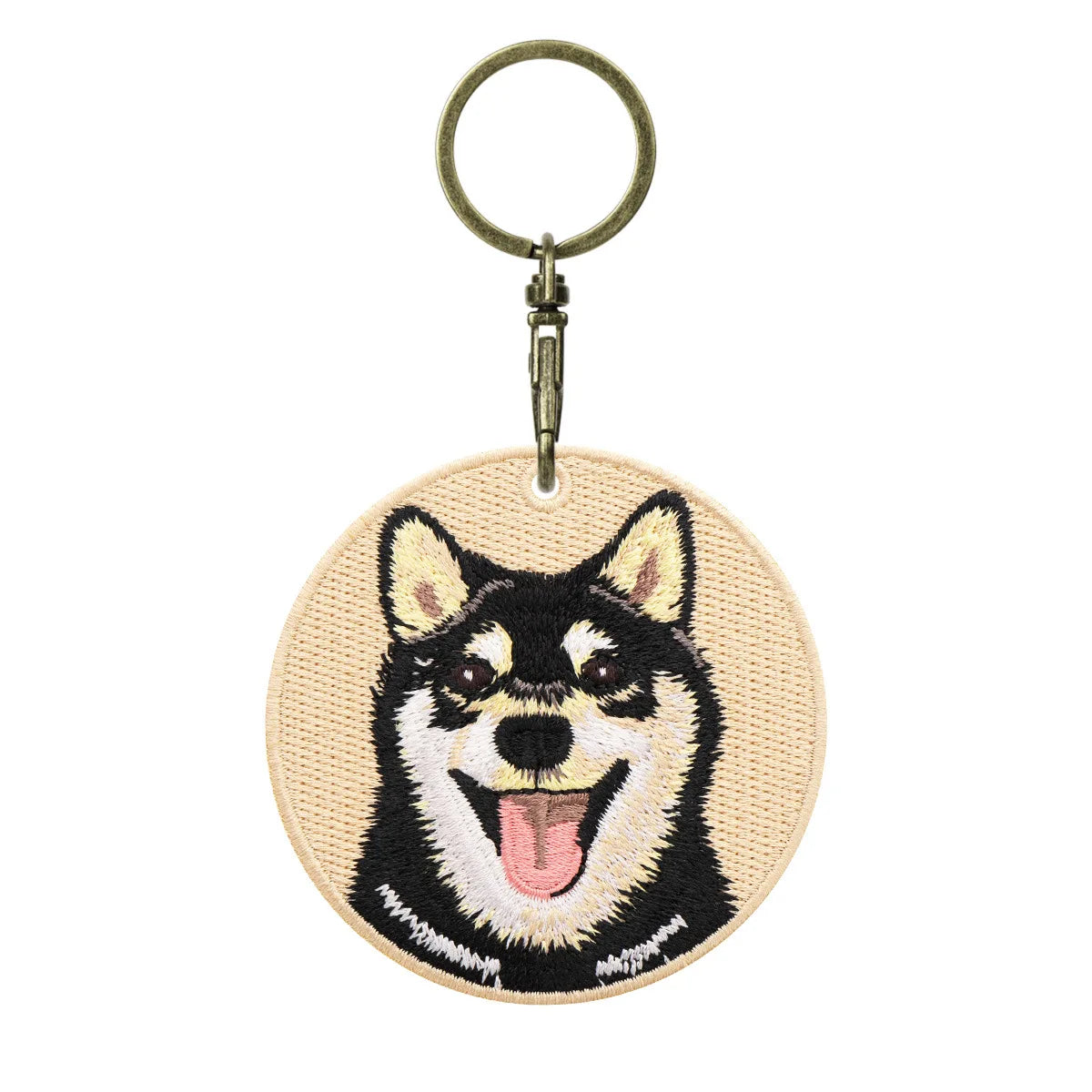 Keychain with embroidered dog face design on a beige background