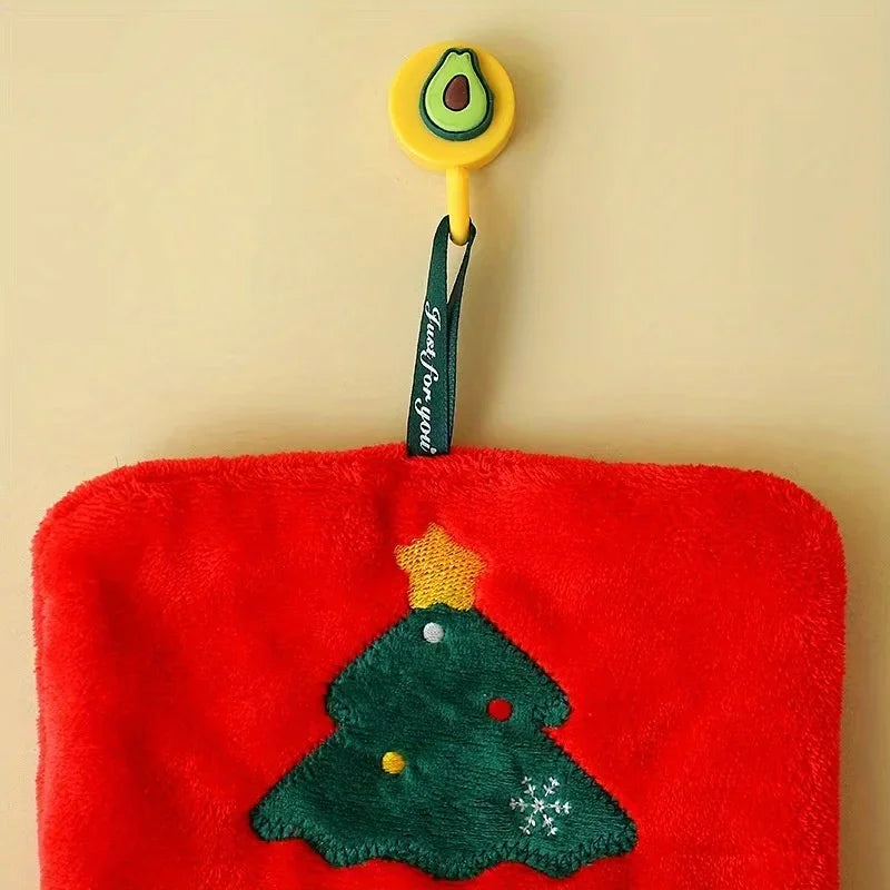 Red plushhand towel with green Christmas tree design and avocado-shaped tag on beige background