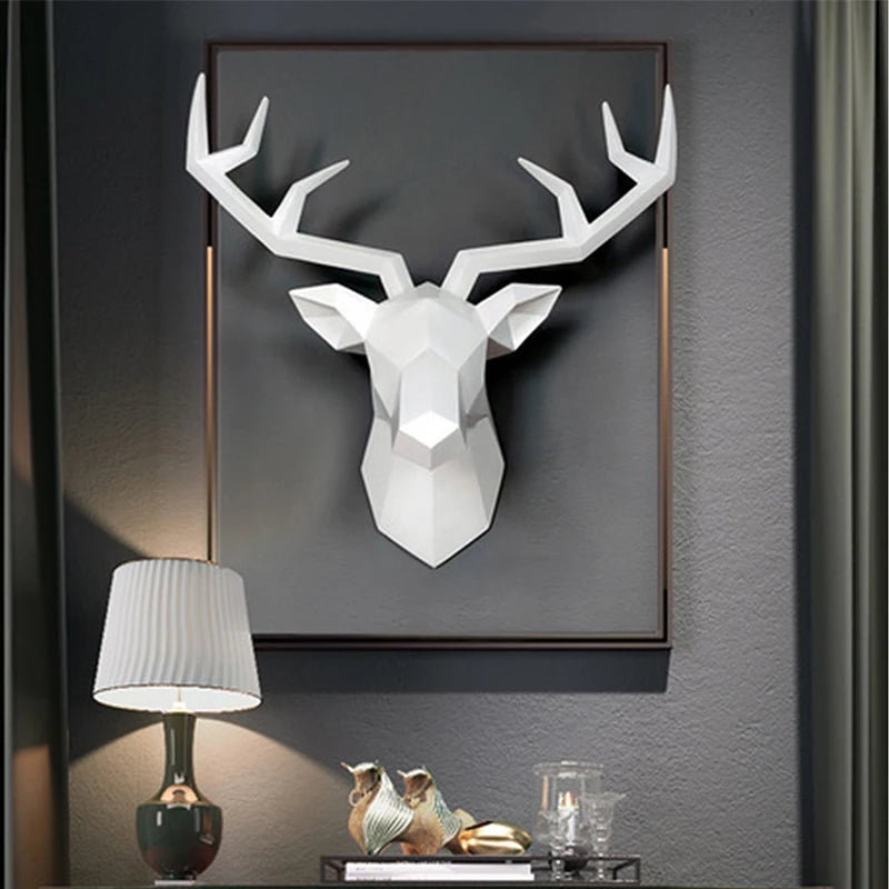 White geometric deer head wall art on a dark gray wall with a lamp and decorative items below.