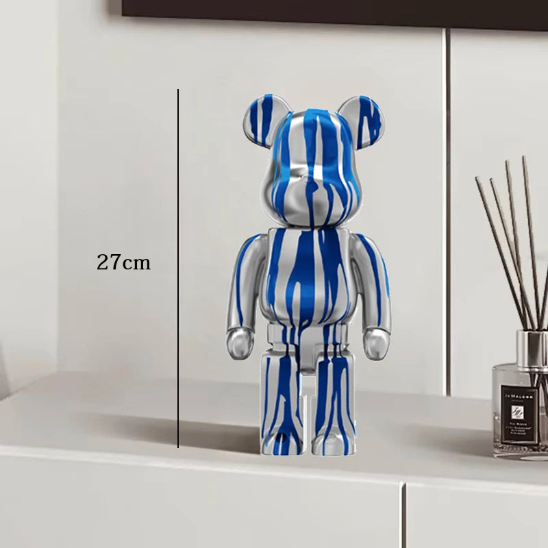 Blue and silver striped bear-like figure on a white surface with a measurement label