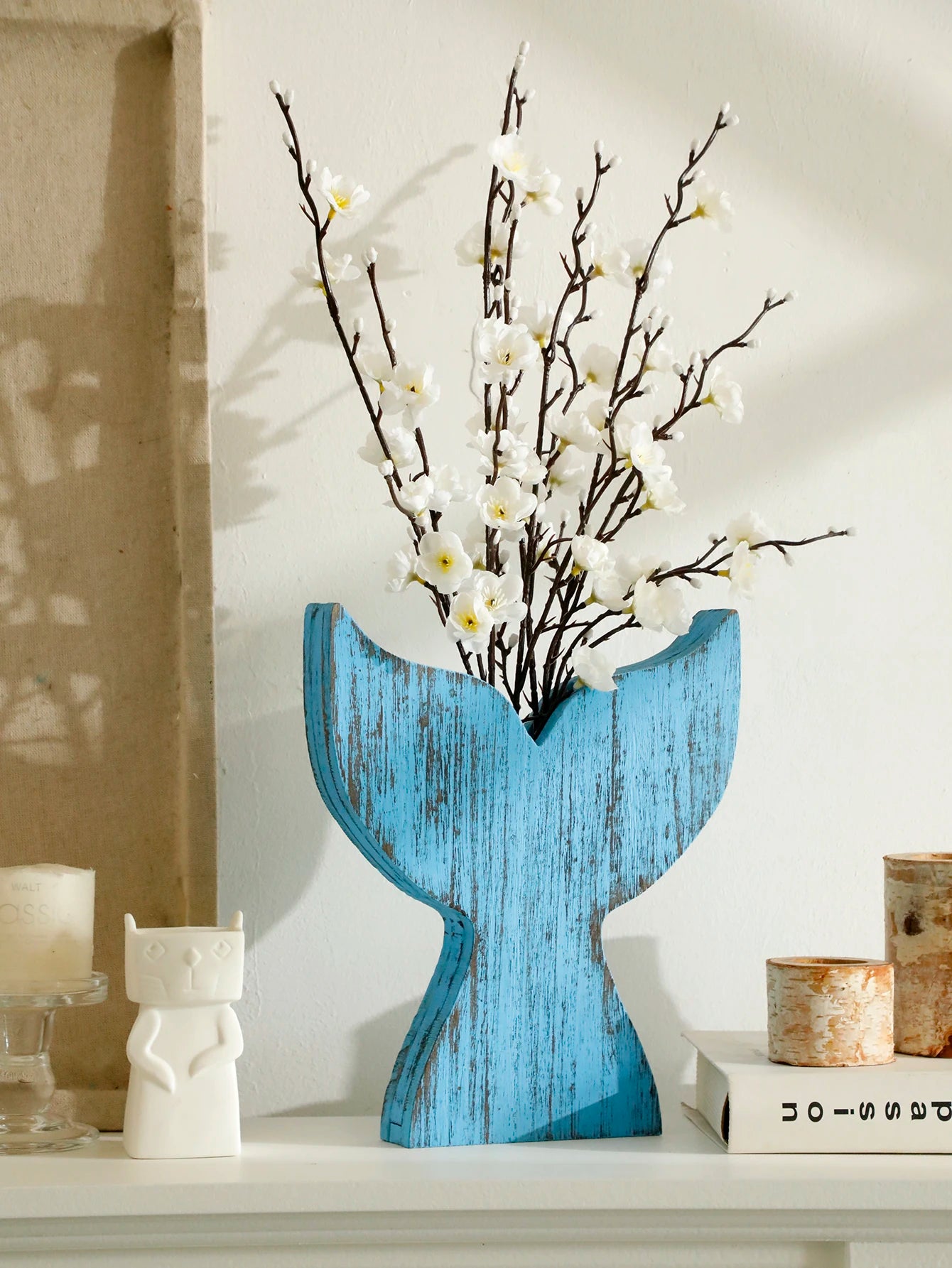 Blue whale tail wooden vase with rustic distressed finish, styled with white blossom branches as coastal home decor.