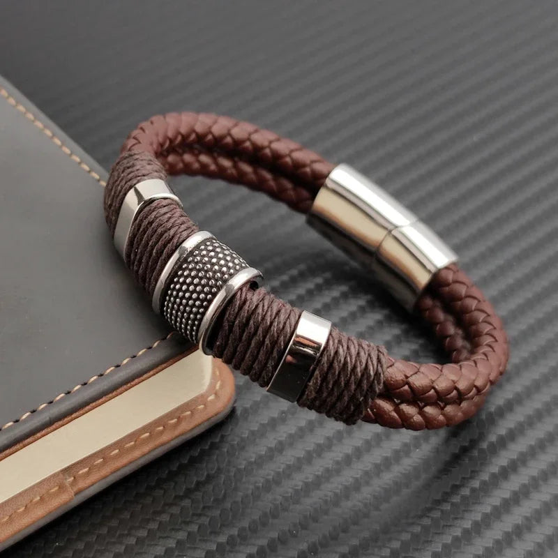 Brown braided bracelet with silver metal clasps on a textured surface