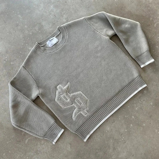 Grey Y2K-style knitted sweater with a boxy fit, round neckline, and subtle raised symbol detail on the front