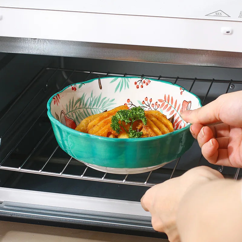 Person placing a decorative bowl with food into an oven.