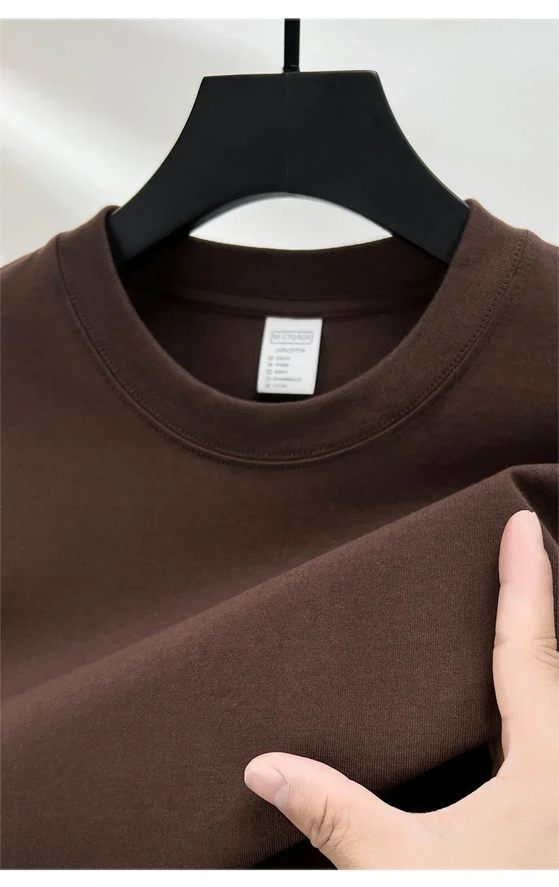 Brown sweatshirt on a hanger with a hand touching the fabric