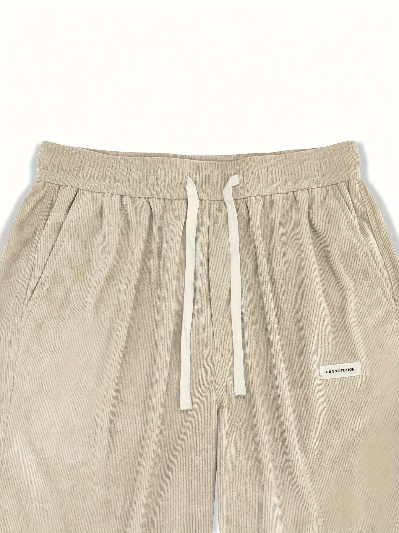 Beige pants with drawstring and brand label on a white background