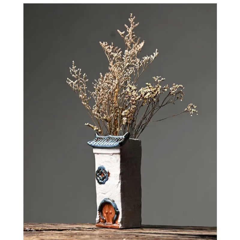 Decorative vase with dried plants on a wooden surface against a gray background
