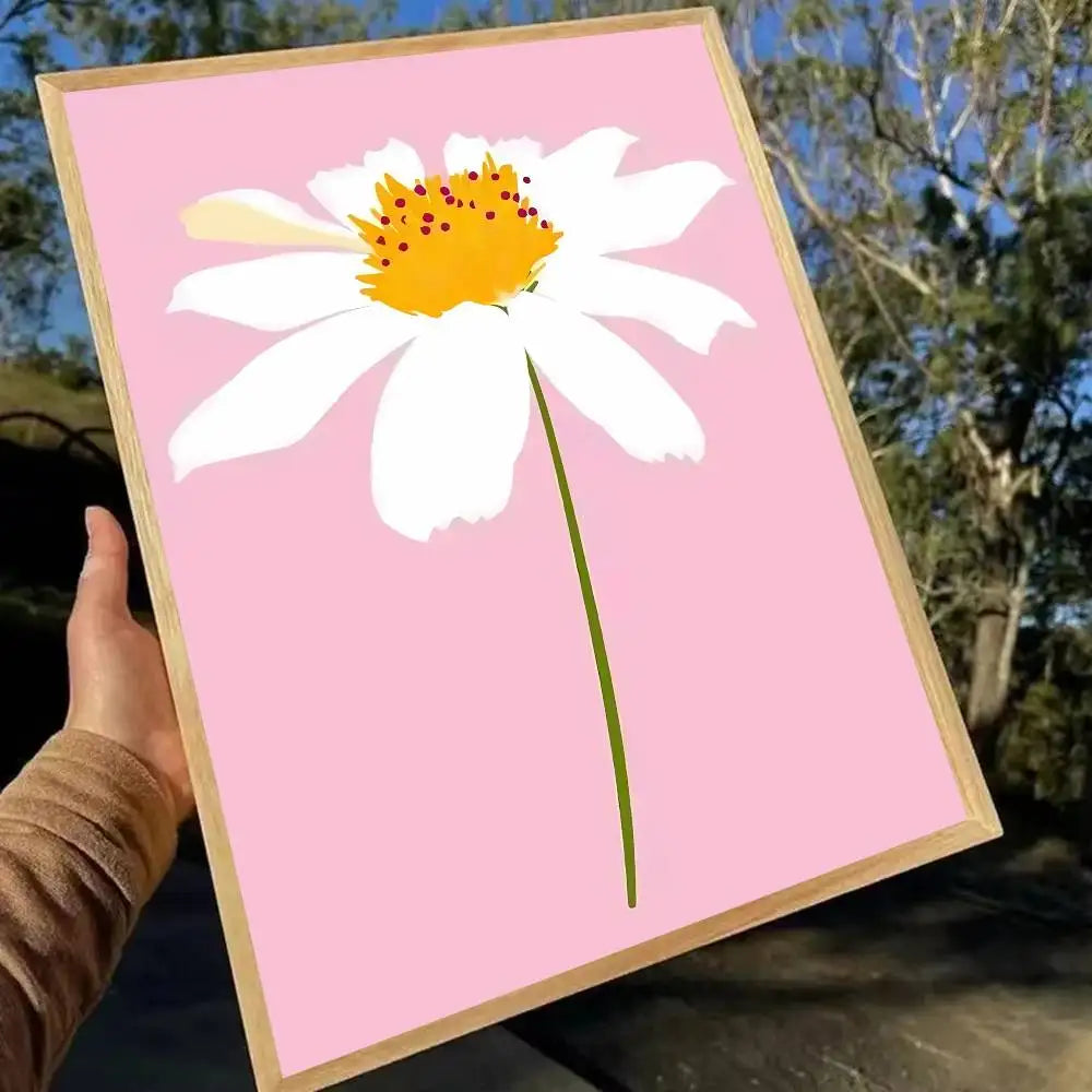 Framed artwork of a white flower with a yellow center on a pink background, held outdoors.