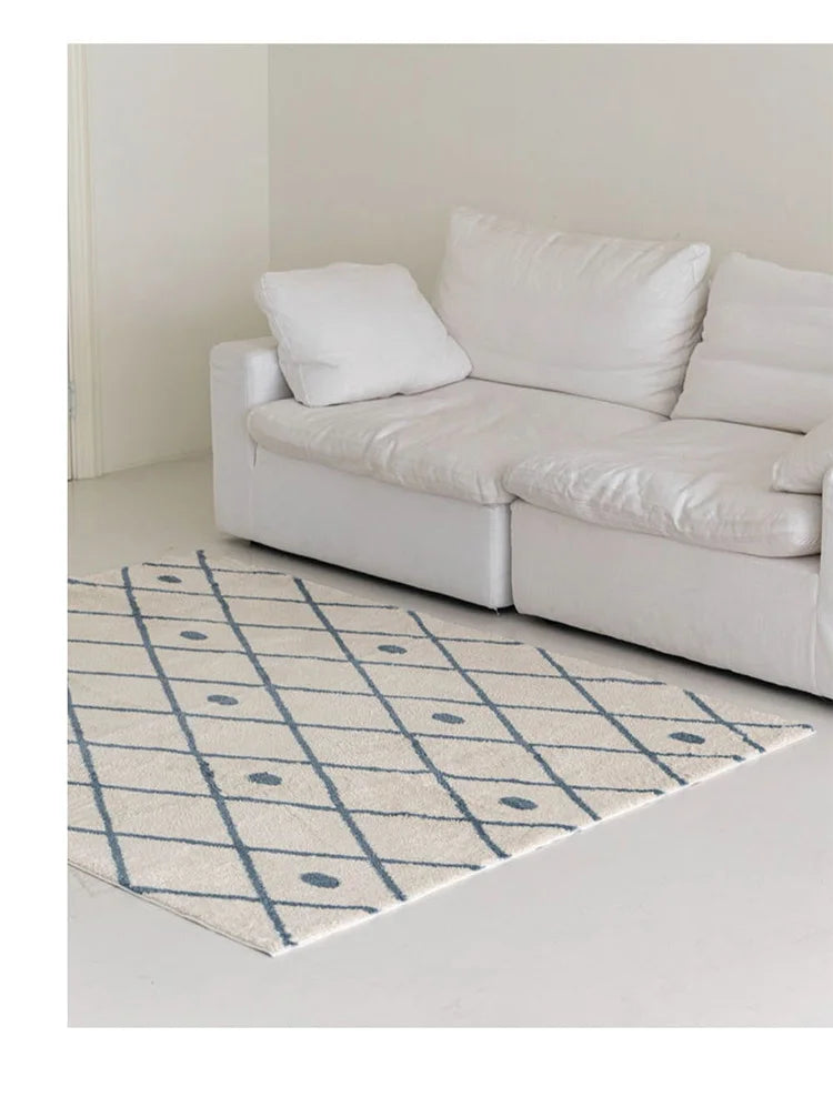 Beige sofa with white cushions on a beige rug with blue grid pattern