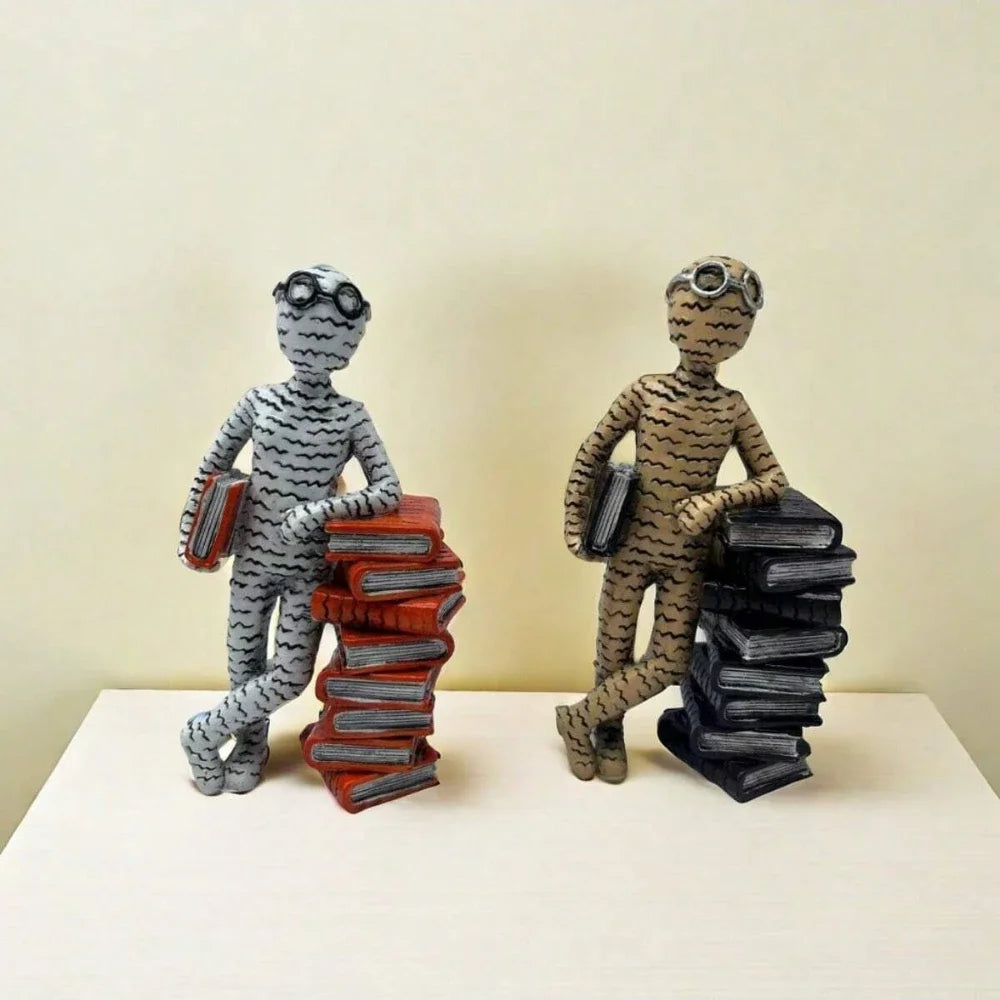 Two Minimalist resin reader statues leaning against a stack of books displayed on a windowsill in a modern home.