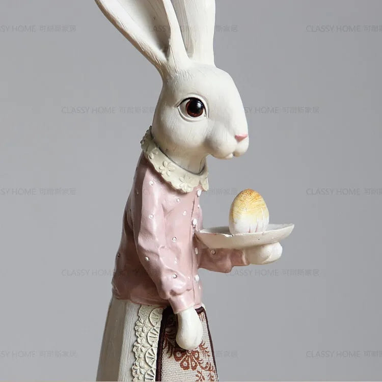 Decorative rabbit figurine holding a plate with an egg against a gray background