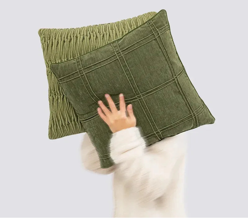 Green textured pillow held by a person against a light gray background