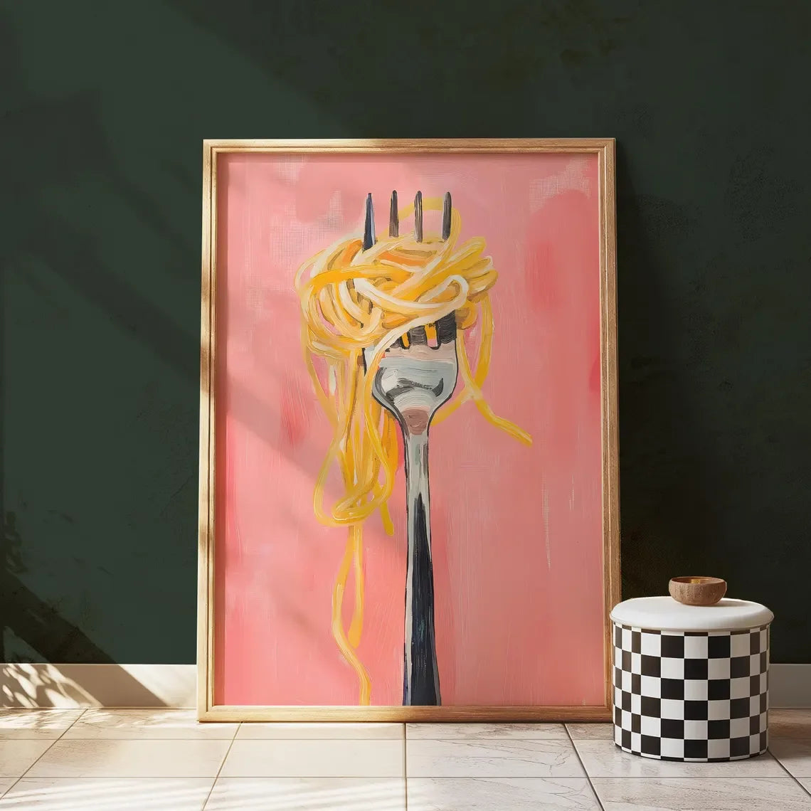 Framed artwork of a fork with spaghetti on a pink background, placed on a wooden floor.