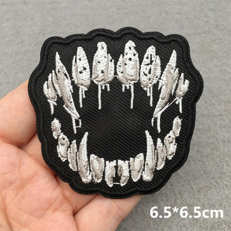 Black and white embroidered patch held in a hand with a gray background