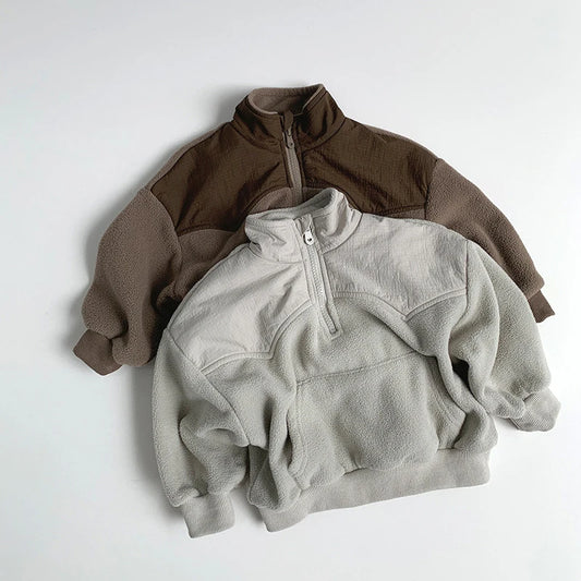 Two fleece pullovers, one brown and one gray, on a light gray background.