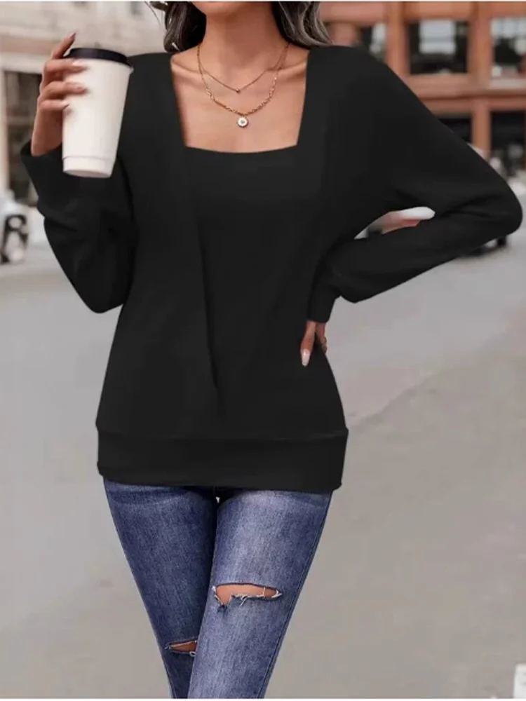Person wearing a black sweater and blue jeans holding a coffee cup outdoors.