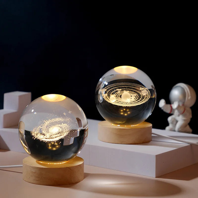 Two glass globes with glowing interior designs on wooden bases against a dark background.