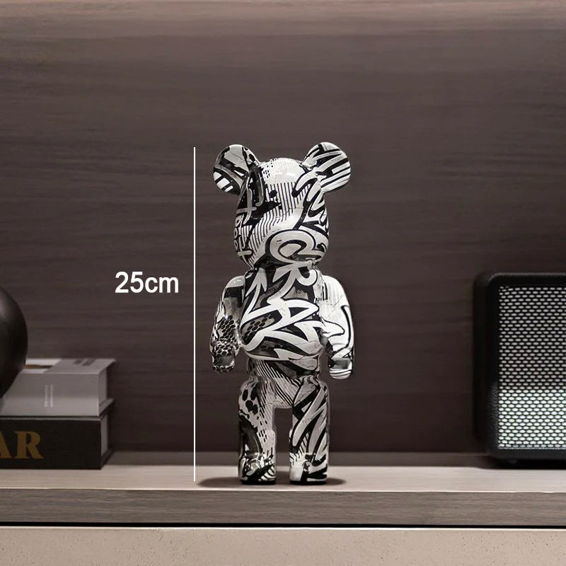 A black and white graffiti-patterned bear figurine standing on a shelf, with a vertical measurement overlay reading 25cm against a dark wood background.