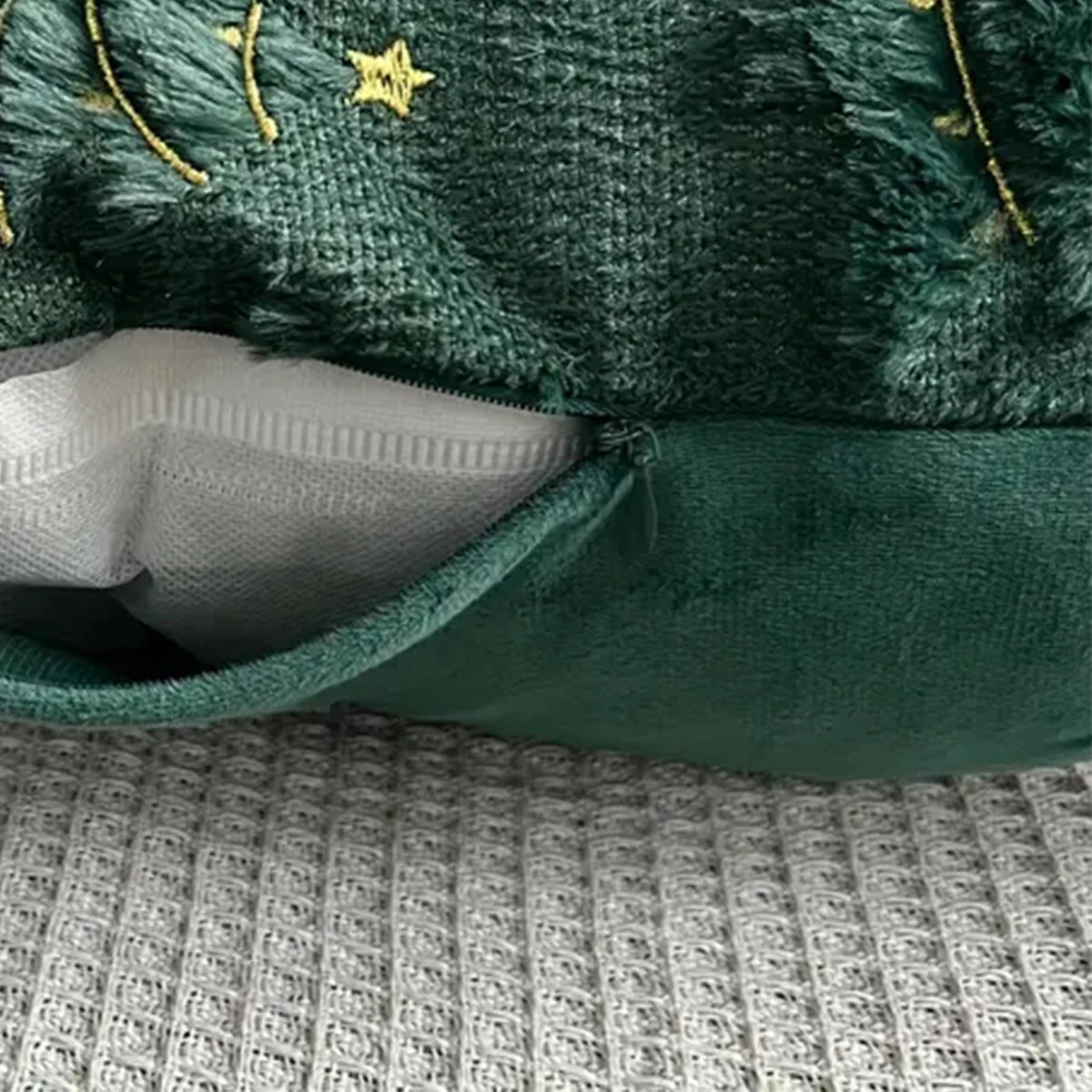 Green texturedpillow cover with a zipper on a patterned surface