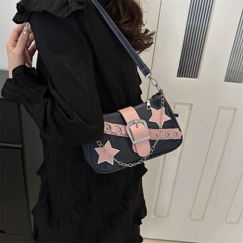 Person wearing a black outfit with a denim handbag featuring pink stars and a silver buckle.