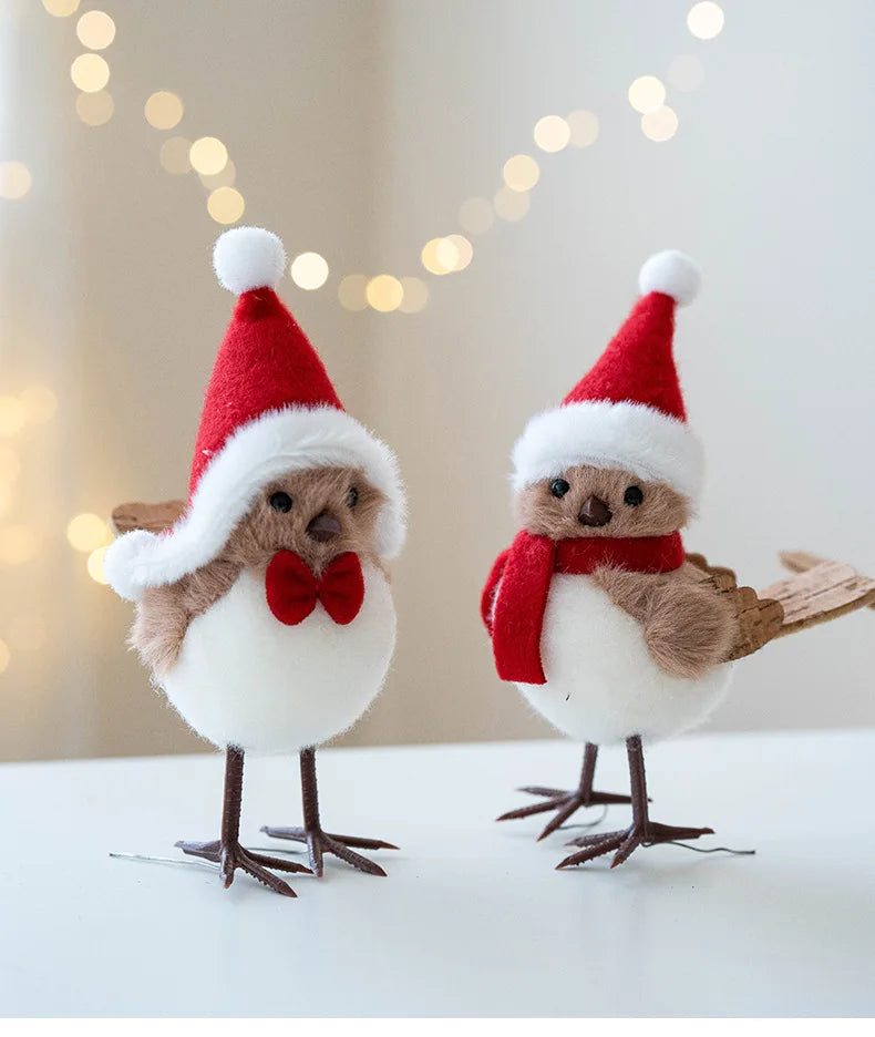 Two festive bird figurines wearing Santa hats and scarves against a blurred light background.
