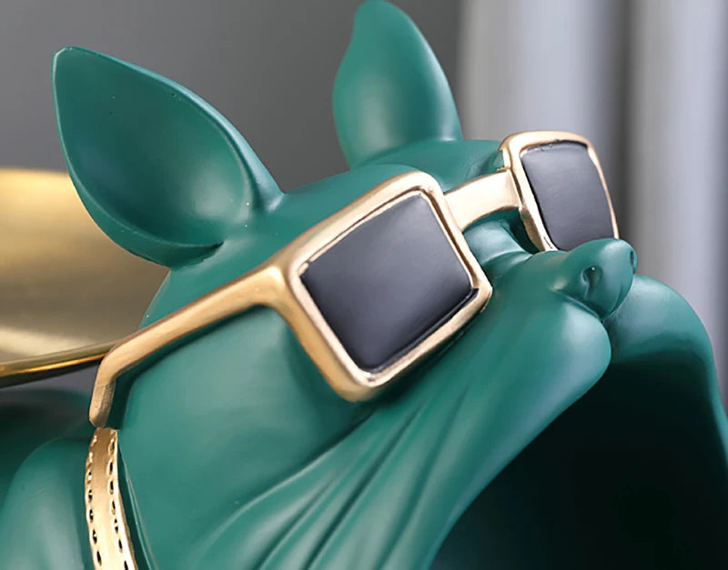 Green animal figurine wearing gold-framed sunglasses with a blurred background