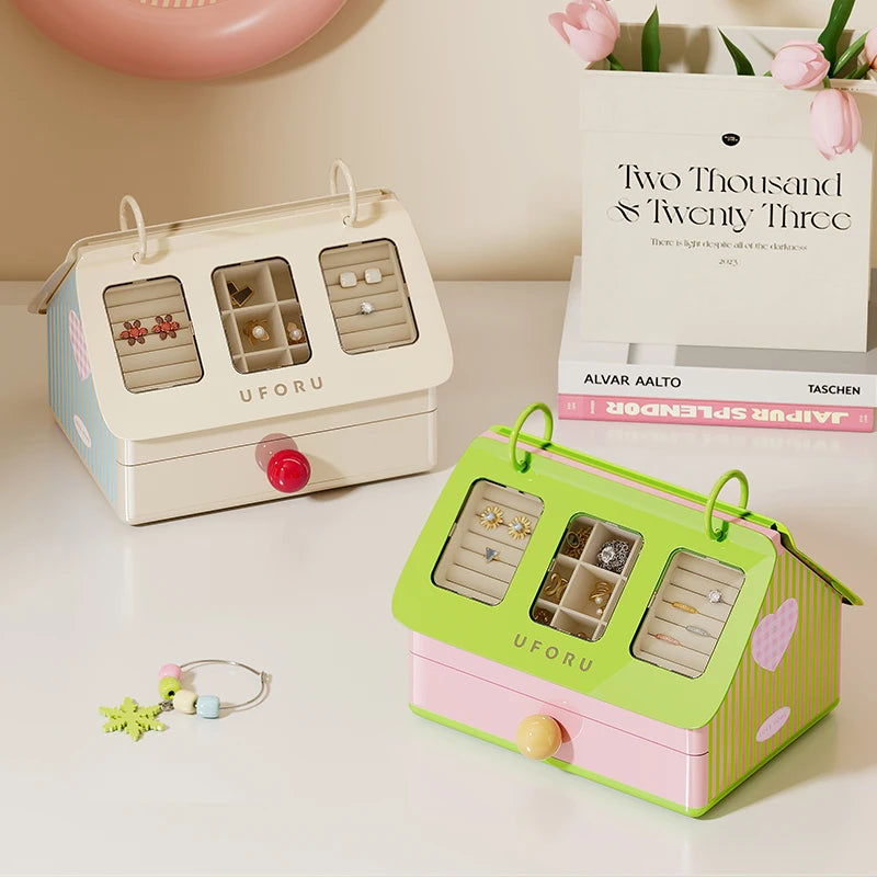 Two jewelry boxes, one beige and one green, on a surface with a book titled 'Two Thousand Twenty Three' in the background.