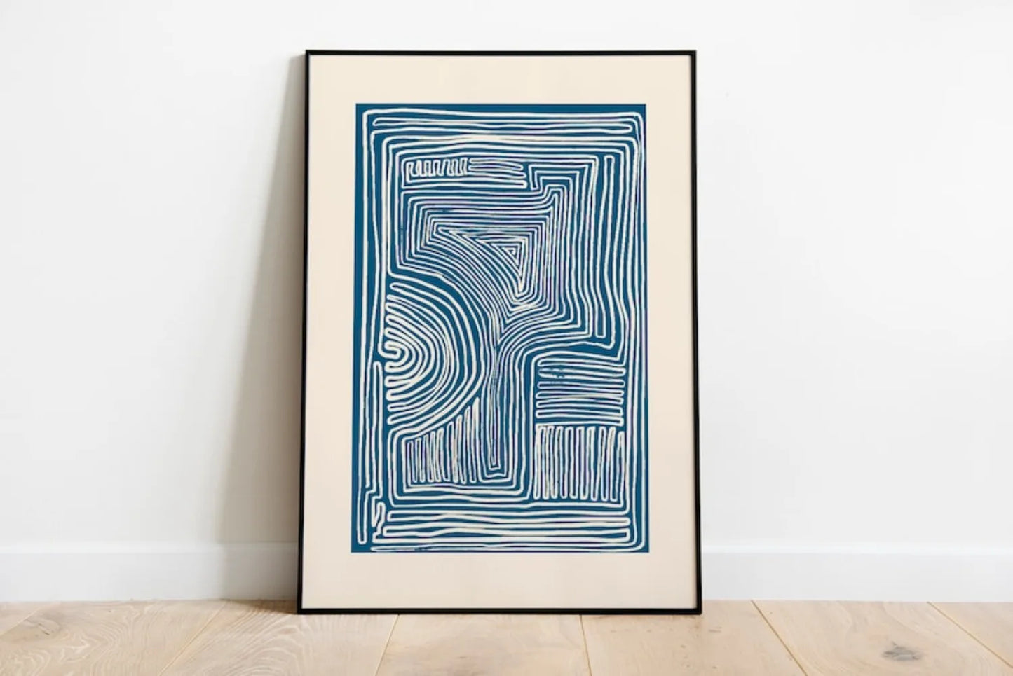 Framed abstract artwork with blue lines on a white wall