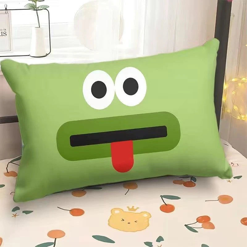 Green pillow with a cartoon face on a bed with a floral pattern