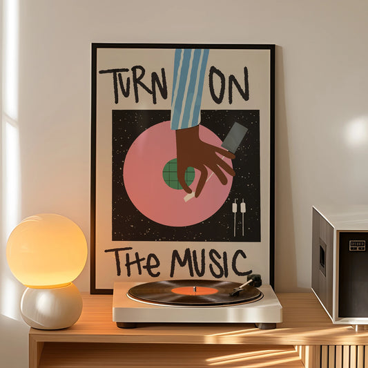 Turn On The Music vinyl record wall art print in black frame above a turntable, featuring pink record design and retro music theme