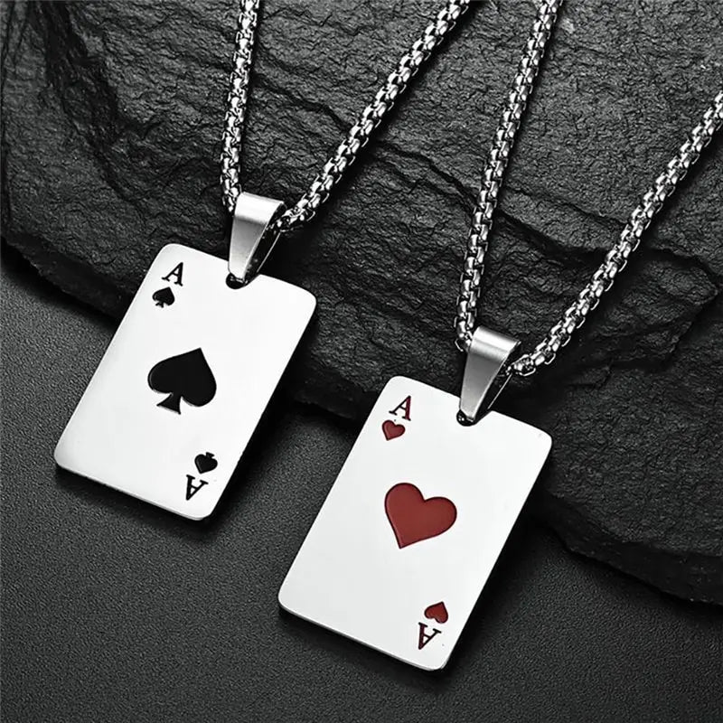 Two silver necklaces with playing card pendants on a dark stone surface
